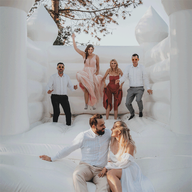 Image animée d'un couple et de ses invités qui sautent sur un château gonflable lors d'un mariage intimiste kermesse original par la photographe d'élopement marie amuse